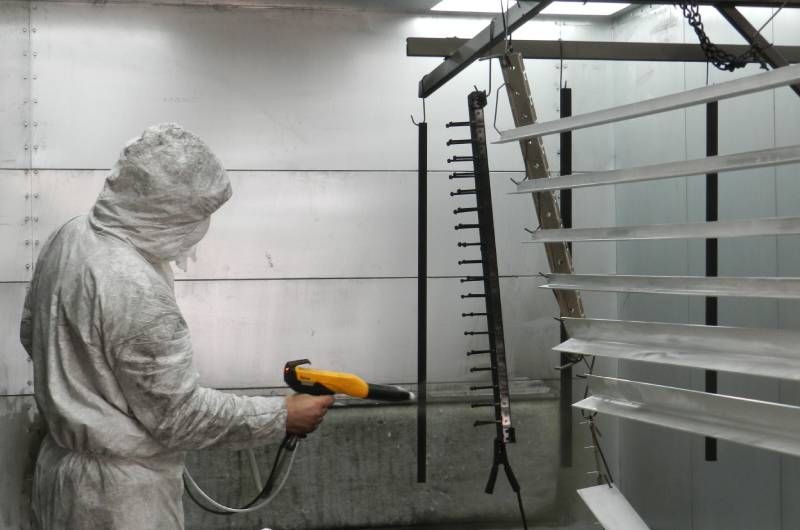 Parasol Awnings employee spraying powder coating onto metal louvers