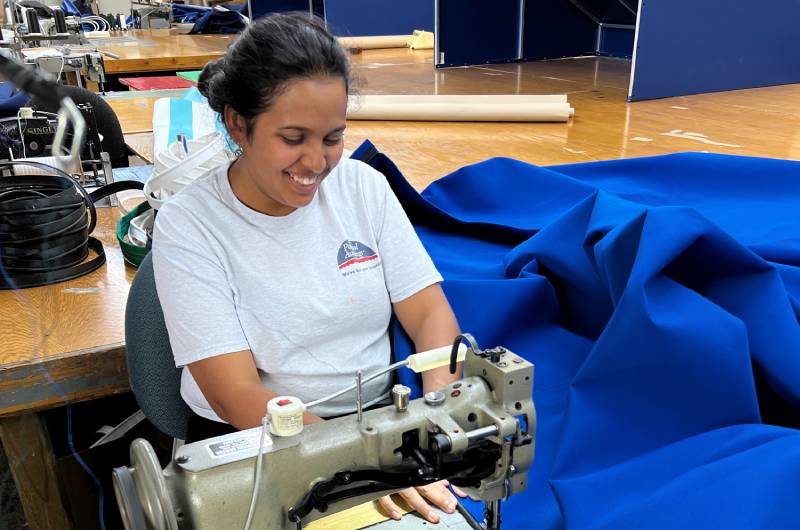 smiling seamstress at work on huge fabric awning